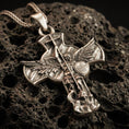 Load image into Gallery viewer, Bronze Saint Michael pendant with winged archangel figure, Quis Ut Deus shield, and devil-slaying cross design displayed on dark volcanic rock in a close-up luxury jewelry composition
