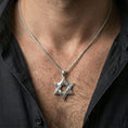Load image into Gallery viewer, Polished silver Star of David necklace with decorative six-pointed star relief worn on the neck in a close lifestyle frame, highlighting the engraved details and symbolic silhouette
