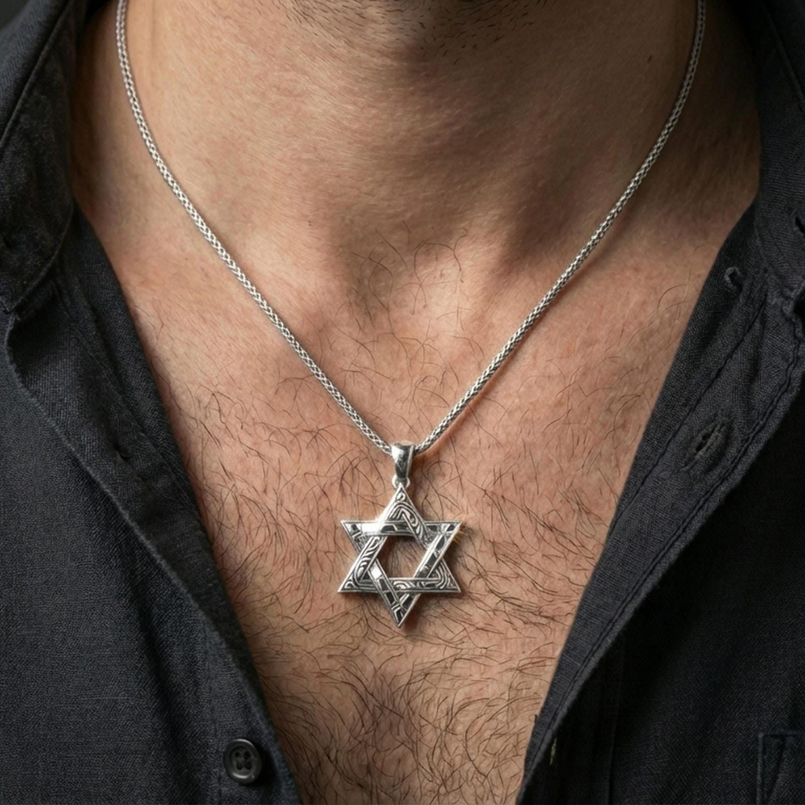 Polished silver Star of David necklace with decorative six-pointed star relief worn on the neck in a close lifestyle frame, highlighting the engraved details and symbolic silhouette
