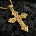 Load image into Gallery viewer, Gold plated Celtic cross pendant with continuous knot motif, decorative open structure, and elongated symbolic form showcased on black volcanic rock in a refined macro jewelry image

