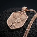Load image into Gallery viewer, Rose gold plated Saint Michael shield pendant necklace on dark volcanic rock, photographed in a detailed premium studio macro view.
