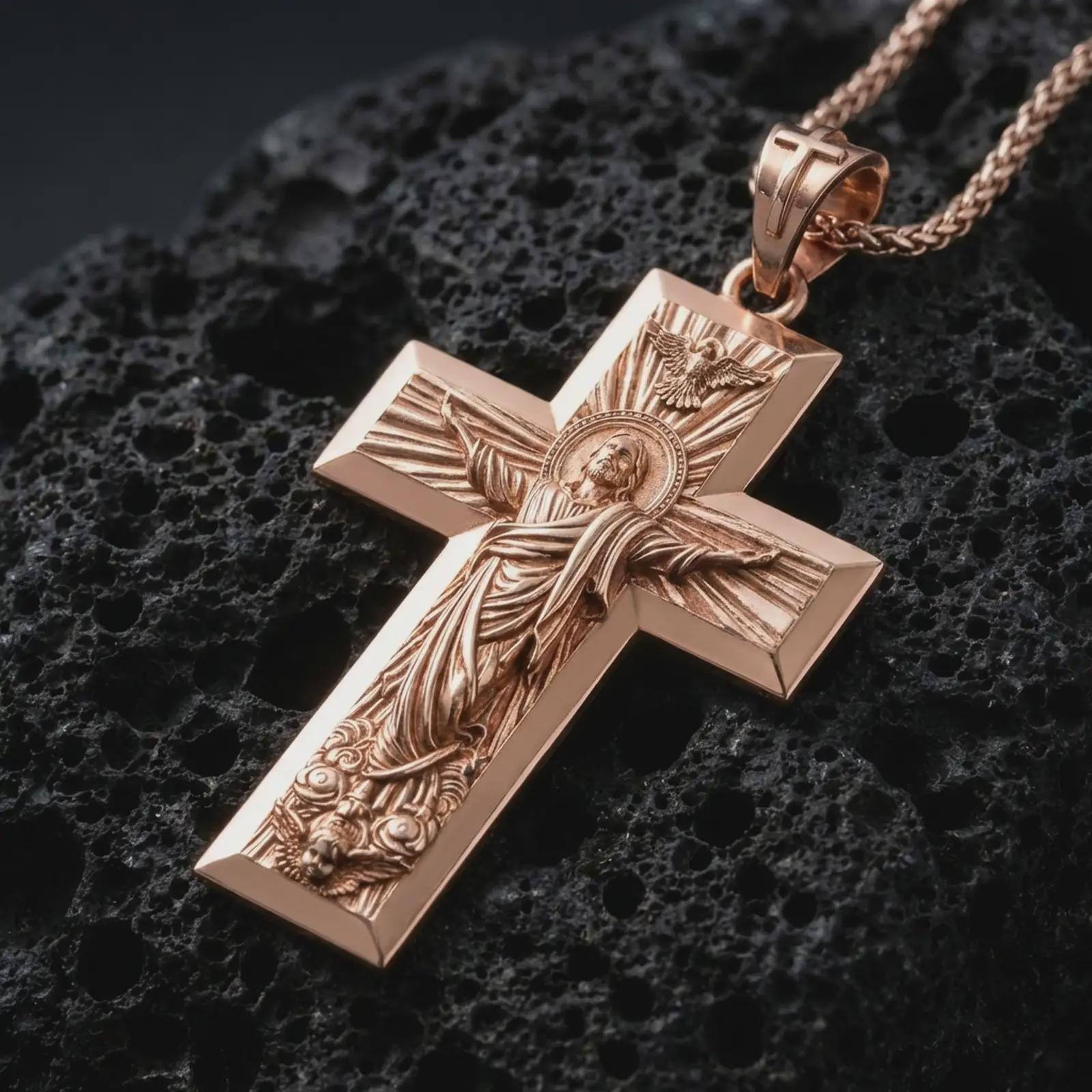 Rose gold plated Jesus Ascension cross pendant necklace on dark volcanic rock, photographed in a detailed premium studio macro view.