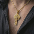 Load image into Gallery viewer, Gold plated Celtic cross pendant necklace worn on the neck, captured on a human model in a premium dark-toned lifestyle frame.
