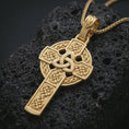 Load image into Gallery viewer, Gold plated Celtic cross pendant necklace presented on porous volcanic rock, highlighting the sacred knotwork design in a luxurious close-up jewelry image.
