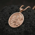 Load image into Gallery viewer, Rose gold plated Saint Benedict pendant necklace on dark volcanic rock, photographed in a detailed premium studio macro view.
