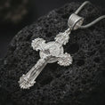 Load image into Gallery viewer, Polished silver Saint Benedict crucifix necklace displayed on black volcanic rock, shown in a refined macro product shot with detailed corpus figure and medallion center.
