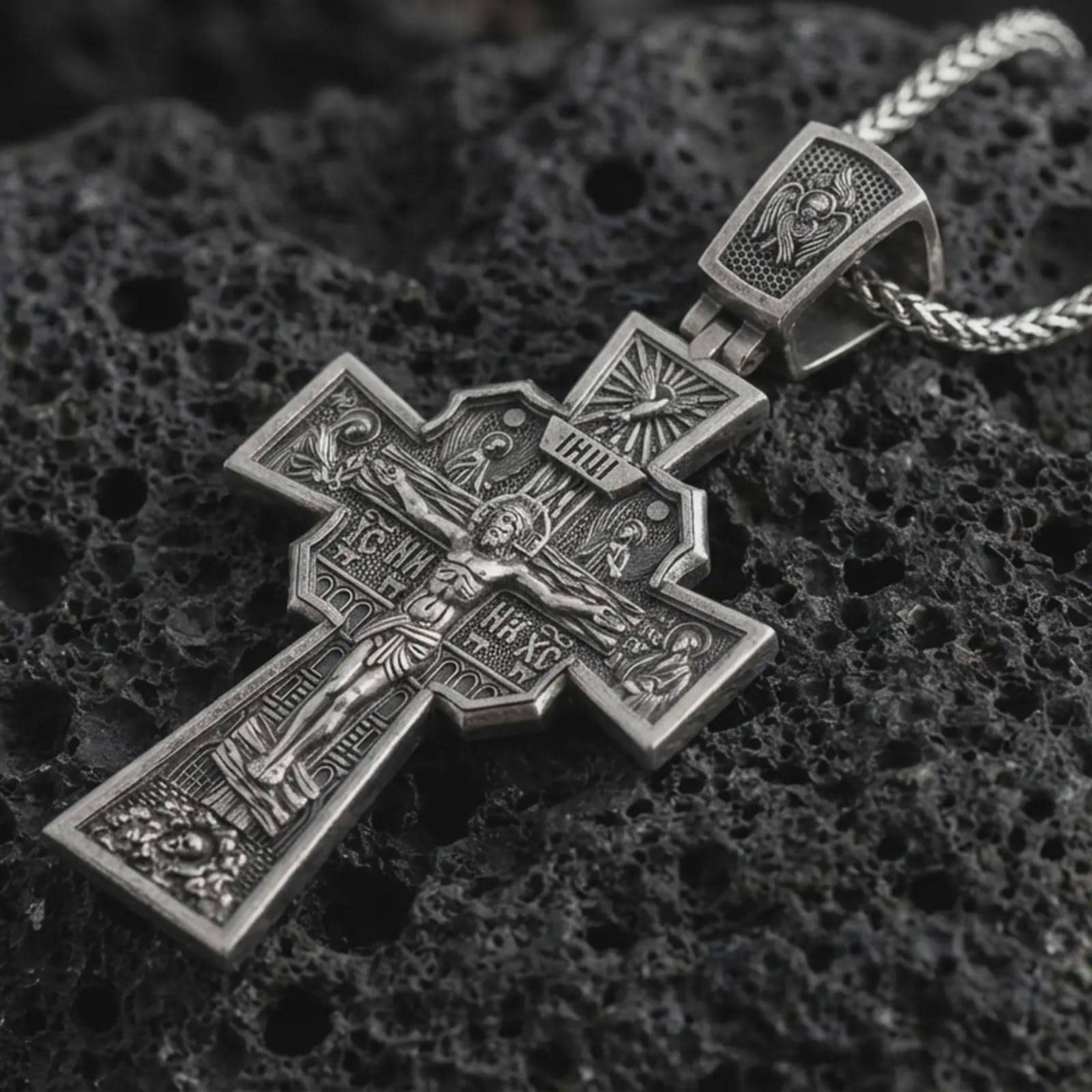 Sterling silver Orthodox cross pendant necklace with an oxidized finish resting on textured volcanic rock, captured in a close-up premium studio composition.