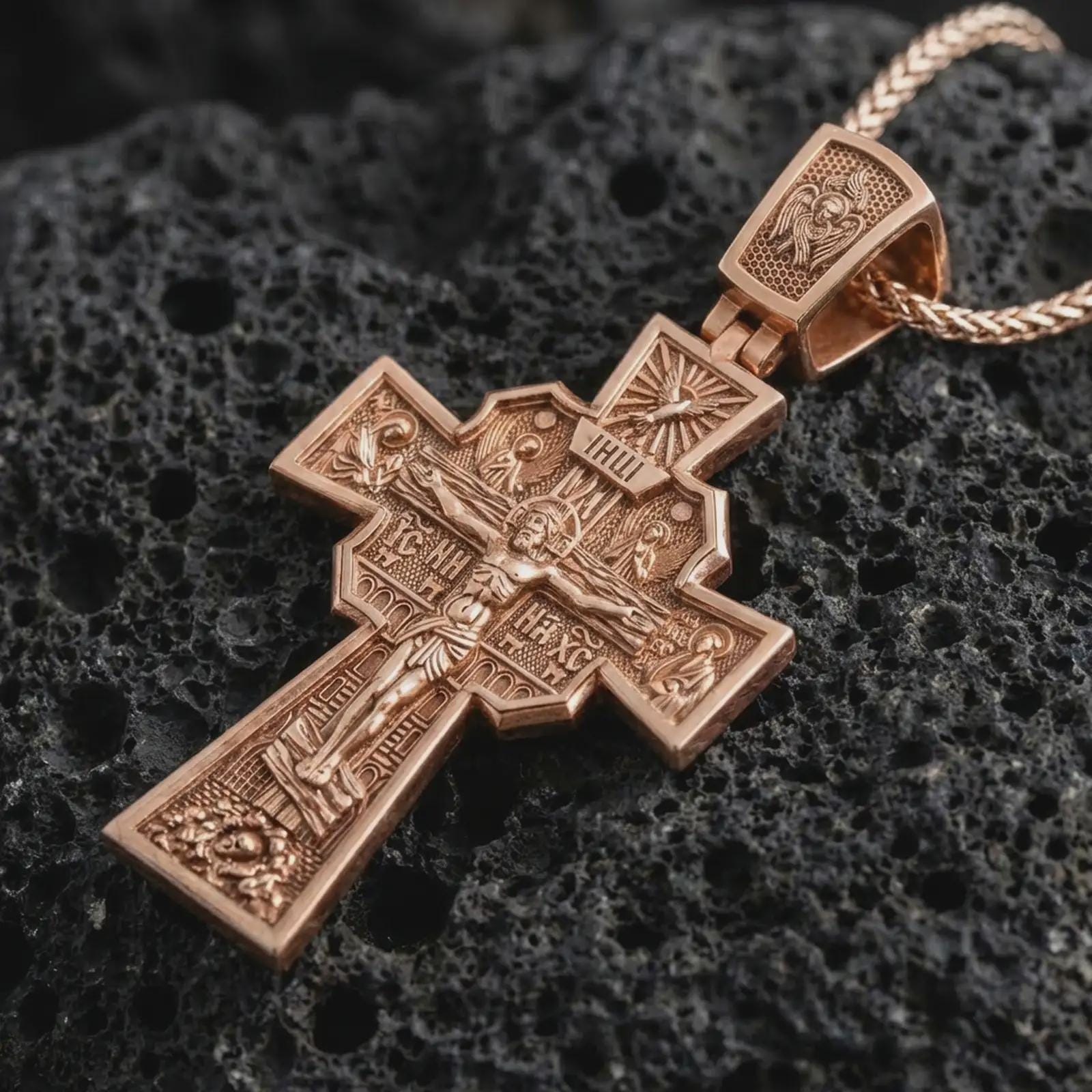 Rose gold plated Orthodox cross pendant necklace on dark volcanic rock, photographed in a detailed premium studio macro view.