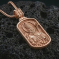 Load image into Gallery viewer, Rose gold plated Saint Patrick dog tag pendant necklace on dark volcanic rock, photographed in a detailed premium studio macro view.
