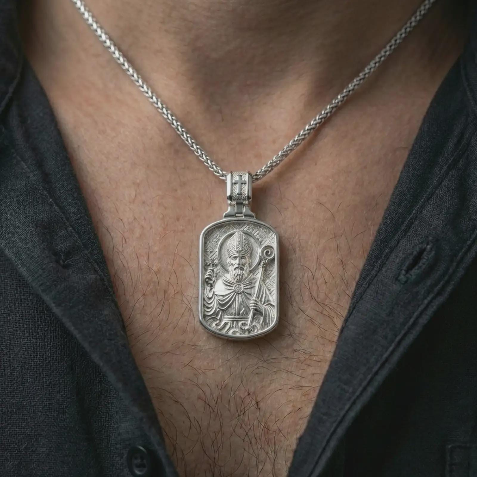 Polished silver Saint Patrick dog tag pendant necklace worn on the neck, shown against the chest in a clean and elegant everyday wear composition.