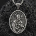 Load image into Gallery viewer, Sterling silver Saint Peter pendant necklace with an oxidized finish resting on textured volcanic rock, captured in a close-up premium studio composition.
