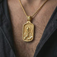 Load image into Gallery viewer, Gold plated Saint Benedict dog tag pendant necklace worn on the neck, captured on a human model in a premium dark-toned lifestyle frame.

