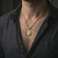 Load image into Gallery viewer, Gold plated Saint Martin of Tours pendant necklace worn on the neck, captured on a human model in a premium dark-toned lifestyle frame.

