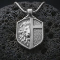 Load image into Gallery viewer, A polished 925 sterling silver shield necklace on volcanic rock featuring a lion profile and raised cross design.
