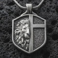 Load image into Gallery viewer, A 925 sterling silver lion cross shield pendant on black volcanic stone with oxidized depth and strong relief details.
