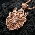 Load image into Gallery viewer, Rose gold plated stag pendant with flower-adorned antlers, intricate botanical detailing, and elegant woodland silhouette resting on volcanic rock in an elegant close-up product presentation

