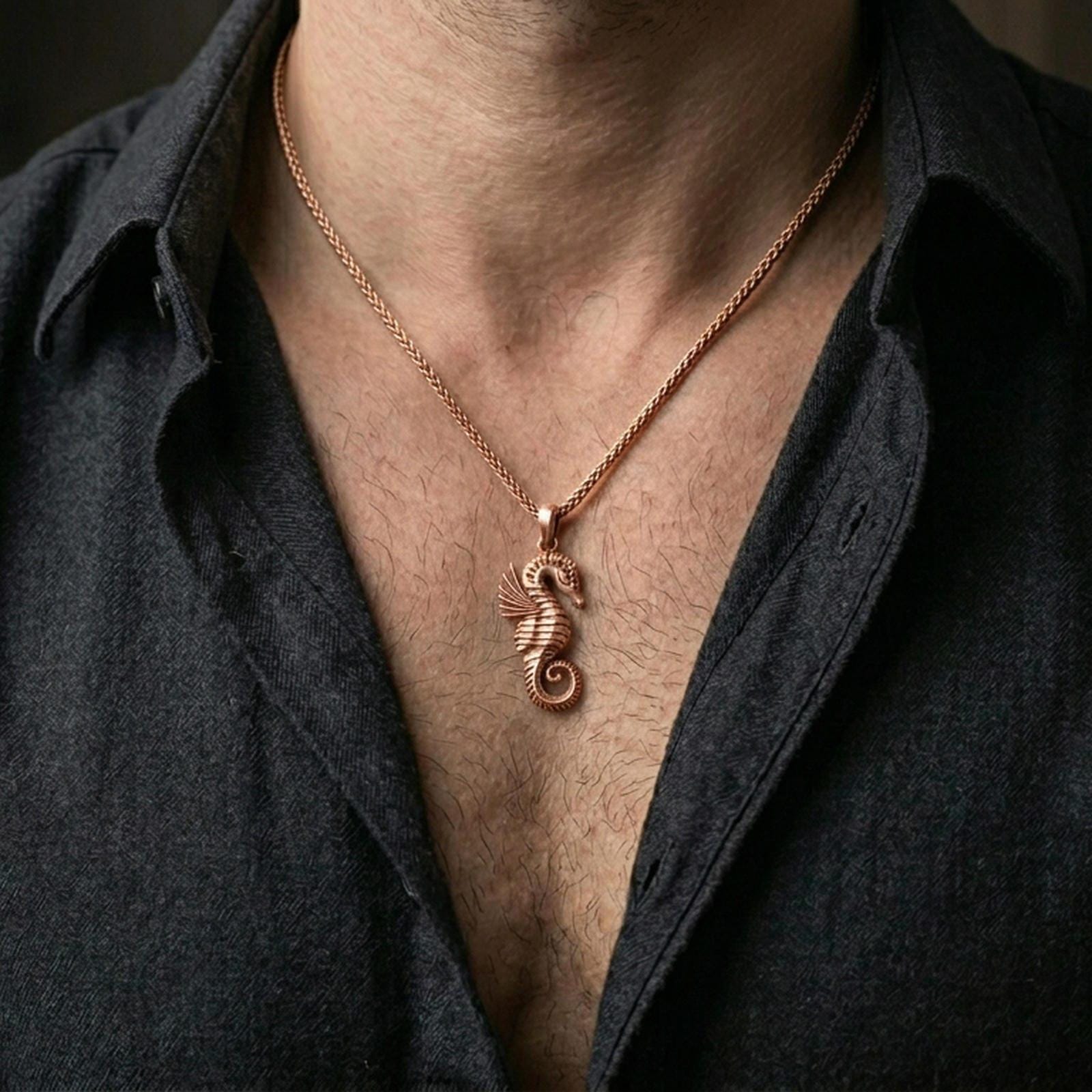 Rose gold plated seahorse necklace with detailed marine relief and curled tail design worn on the neck in a refined lifestyle shot with a warm and elegant presentation