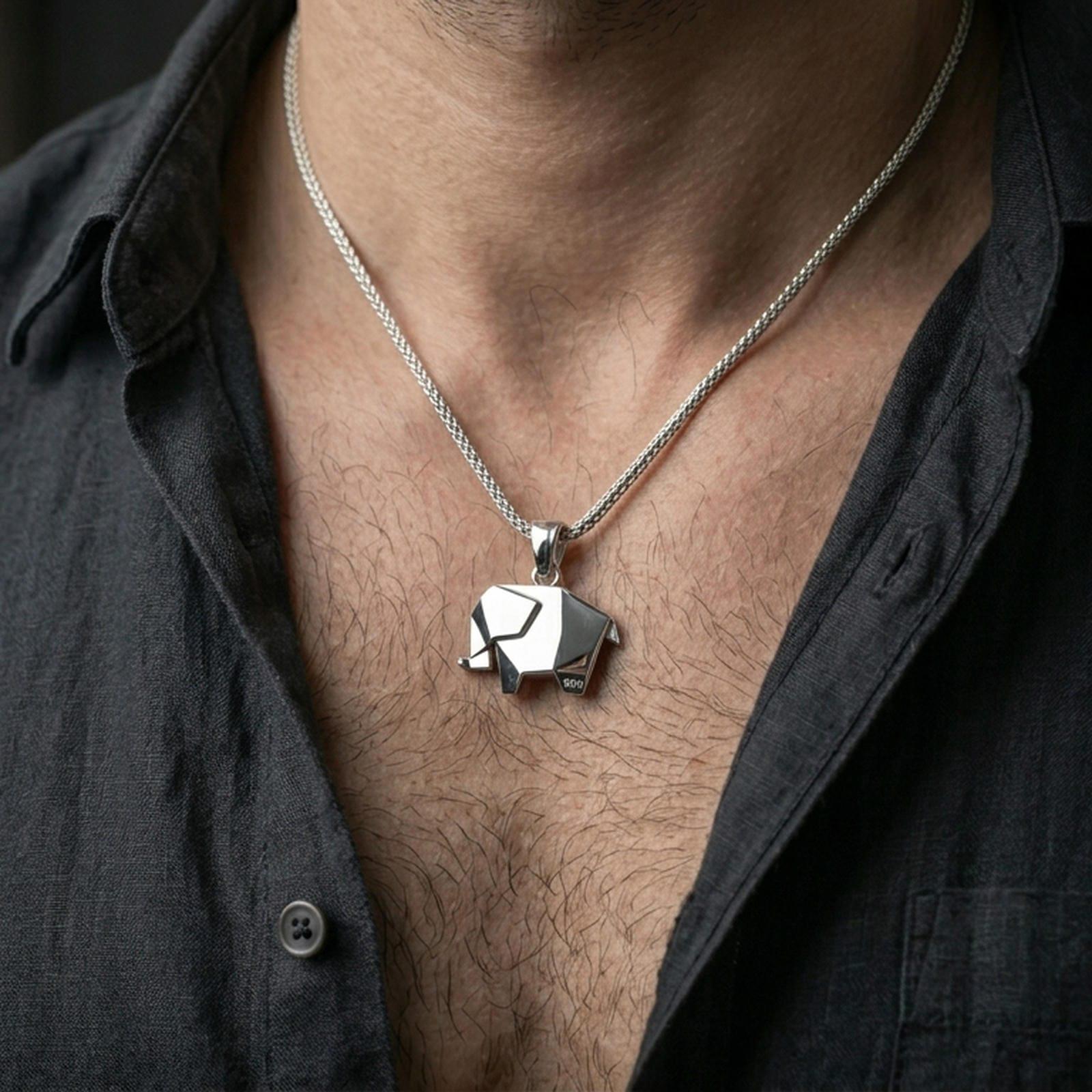 Polished silver elephant necklace with geometric folded form worn on the neck in a close lifestyle frame, highlighting the clean origami lines and modern animal silhouette