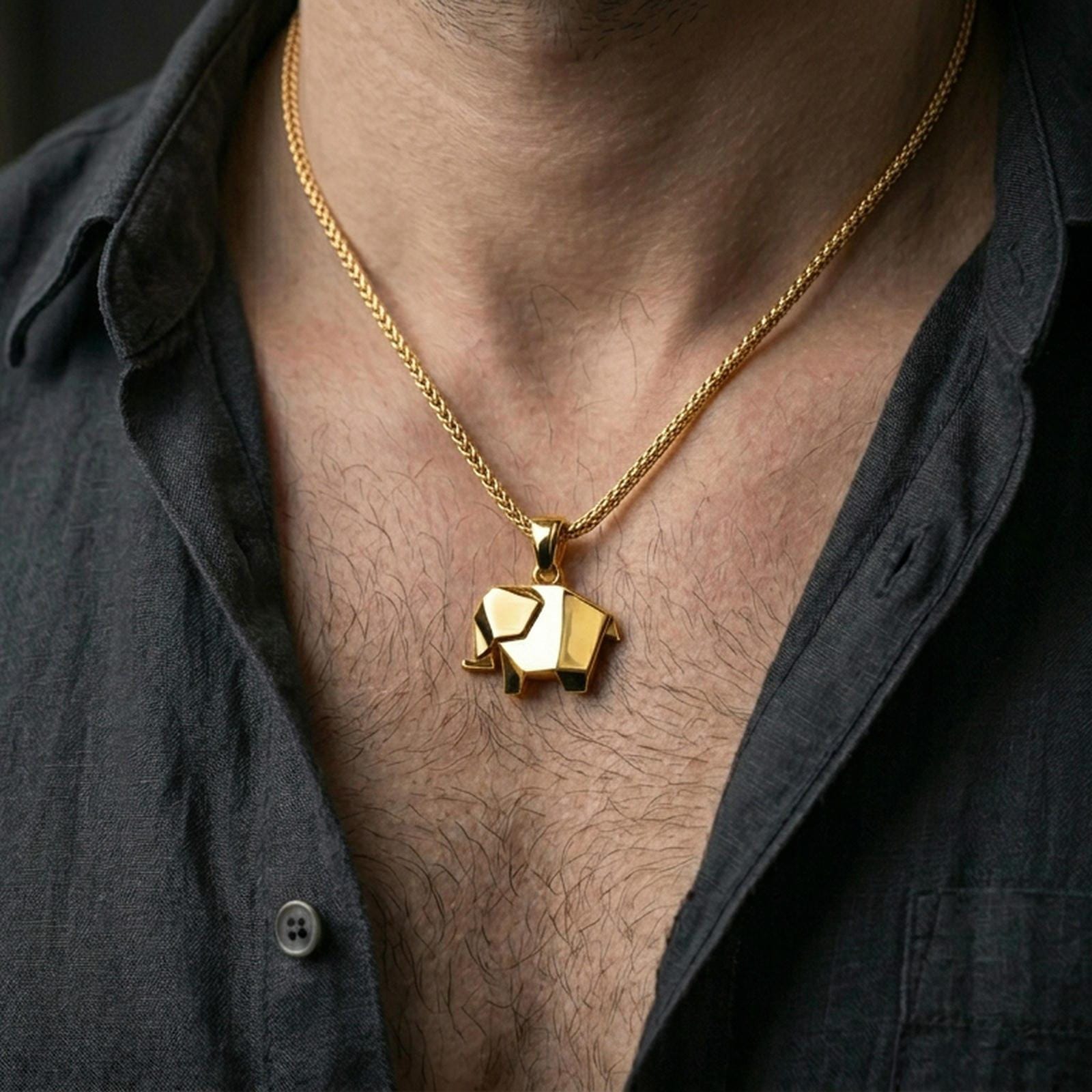Gold plated origami elephant pendant with angular minimalist design worn on the neck in a premium lifestyle composition with refined contemporary jewelry styling