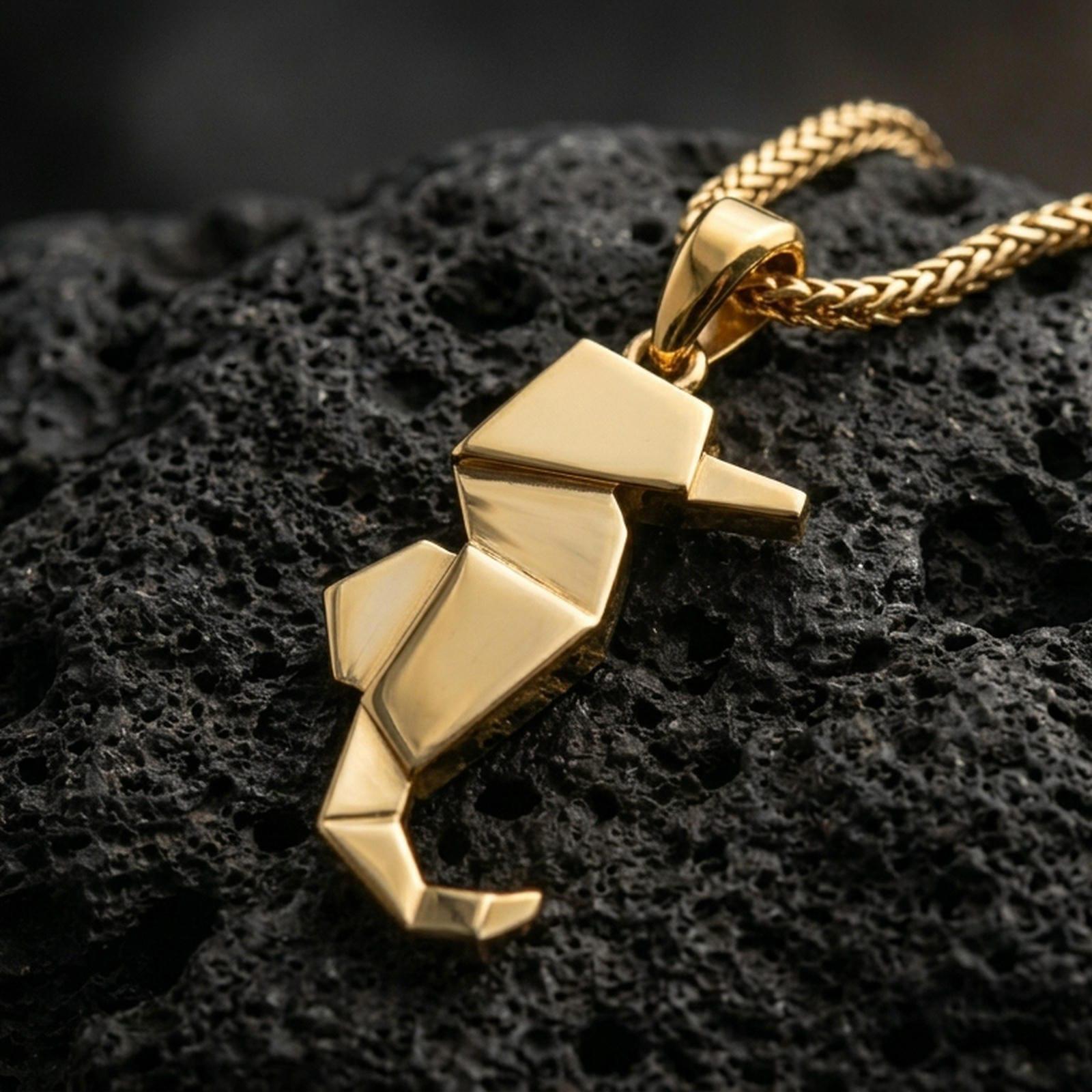 Gold plated origami seahorse pendant with geometric folded body, minimalist ocean-inspired design, and modern sculptural silhouette showcased on black volcanic rock in a refined macro jewelry image