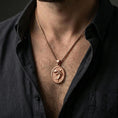 Load image into Gallery viewer, Rose gold plated shark necklace with sculpted shark figure and textured oval frame worn on the neck in a refined lifestyle shot with a warm and distinctive presentation
