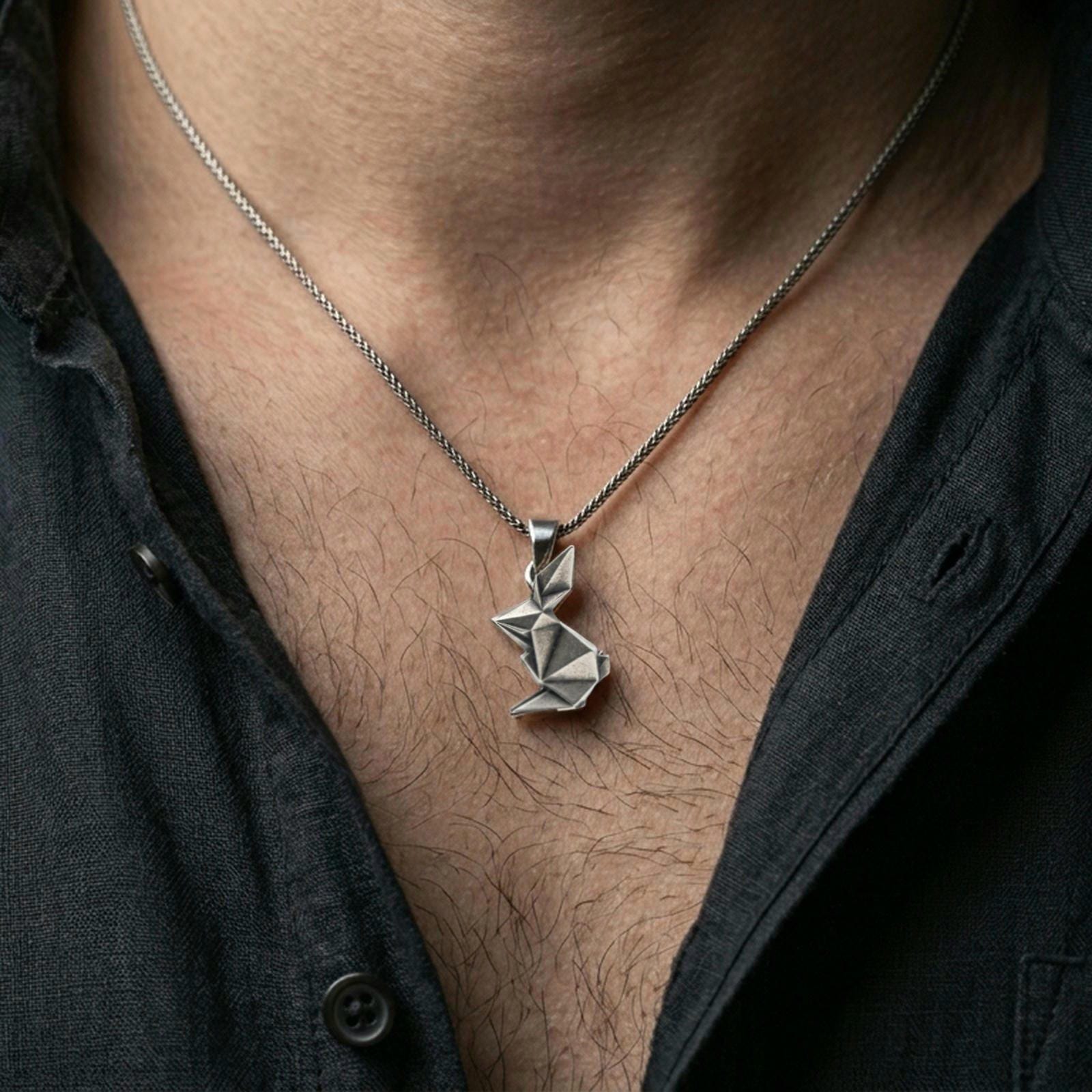 Oxidized origami rabbit pendant worn on the neck in a lifestyle jewelry shot, styled against the chest for a bold and minimalist statement look