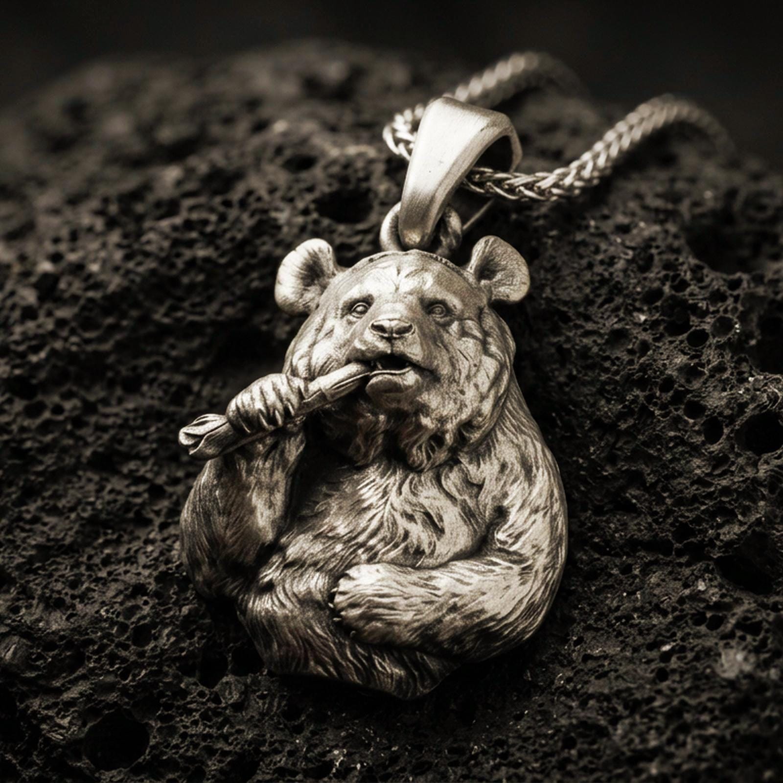 Bronze panda pendant with detailed fur texture, bamboo stalk accent, and playful animal silhouette displayed on dark volcanic rock in a close-up luxury jewelry composition