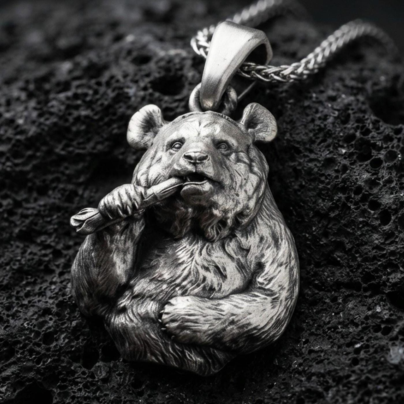 Oxidized panda pendant with detailed fur texture, bamboo stalk accent, and playful animal silhouette displayed on dark volcanic rock in a close-up luxury jewelry composition