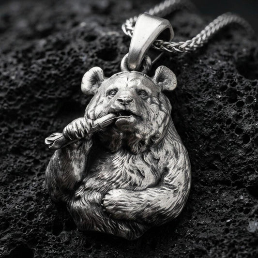 Oxidized panda pendant with detailed fur texture, bamboo stalk accent, and playful animal silhouette displayed on dark volcanic rock in a close-up luxury jewelry composition