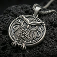 Load image into Gallery viewer, Oxidized owl pendant with detailed feather engraving, round framed silhouette, and symbolic bird of wisdom displayed on dark volcanic rock in a close-up luxury jewelry composition
