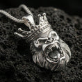 Load image into Gallery viewer, Polished silver gorilla necklace with crowned primate design, fierce open-mouth expression, and sculpted fur detailing placed on textured volcanic rock in a premium studio product shot
