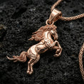 Load image into Gallery viewer, Rose gold plated horse necklace with sculpted stallion body, flowing mane detail, and elegant rearing pose resting on volcanic rock in an elegant close-up product presentation
