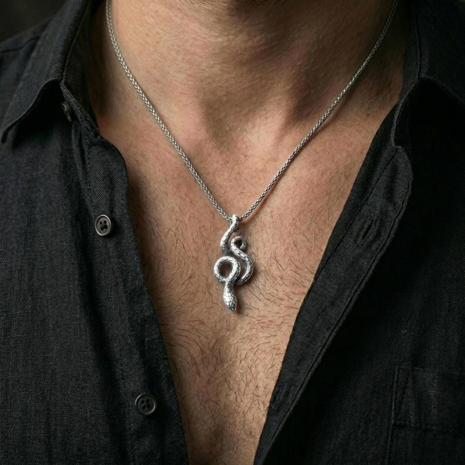 Polished silver serpent necklace with sculpted snake form and detailed scale texture worn on the neck in a close lifestyle frame, highlighting the elegant animal silhouette and fine craftsmanship