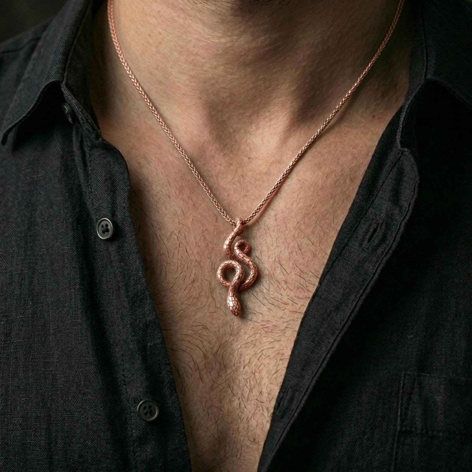 Rose gold plated serpent necklace with coiled snake silhouette, detailed scale relief, and elegant symbolic form worn on the neck in a refined lifestyle shot with a warm and sophisticated presentation