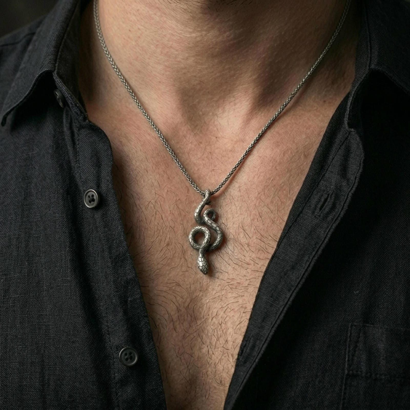 Oxidized snake pendant with winding serpent silhouette worn on the neck in a lifestyle jewelry shot, styled against the chest for a bold and symbolic statement look