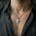 Load image into Gallery viewer, Polished silver frog necklace with sculpted amphibian relief and leaf-shaped base worn on the neck in a close lifestyle frame, highlighting the organic silhouette and refined craftsmanship
