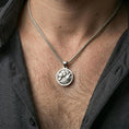 Load image into Gallery viewer, Polished silver wolf necklace with circular medallion shape and detailed twin wolf relief worn on the neck in a close lifestyle frame, highlighting the layered fur texture and powerful animal symbolism
