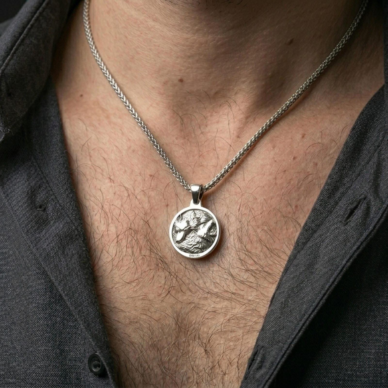 Polished silver wolf necklace with circular medallion shape and detailed twin wolf relief worn on the neck in a close lifestyle frame, highlighting the layered fur texture and powerful animal symbolism