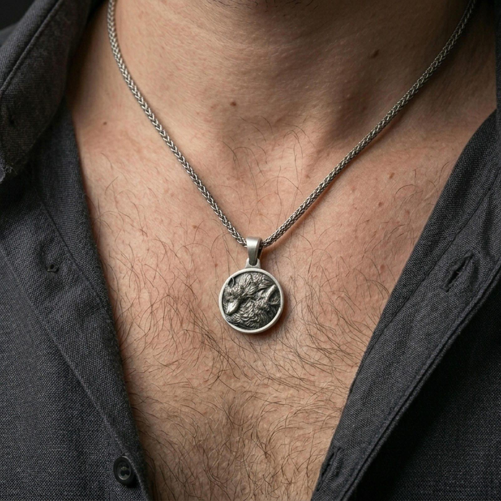 Oxidized twin wolf pendant with howling and resting wolf design worn on the neck in a lifestyle jewelry shot, styled against the chest for a bold and wilderness-inspired statement look
