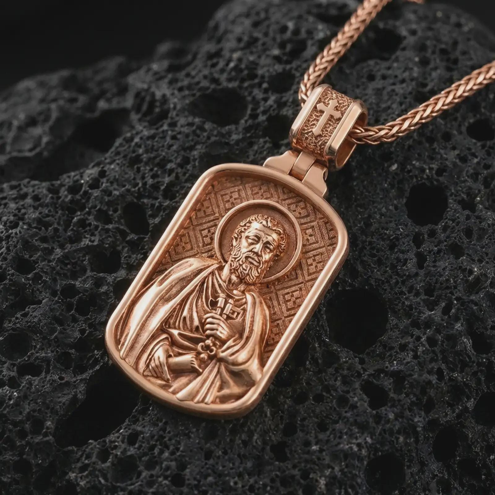 Rose gold plated Saint Peter dog tag pendant necklace on dark volcanic rock, photographed in a detailed premium studio macro view.