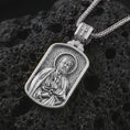 Load image into Gallery viewer, Polished silver Saint Peter dog tag pendant necklace displayed on black volcanic rock, shown in a refined macro product shot with detailed saint figure, key, and engraved background pattern.
