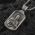 Load image into Gallery viewer, Sterling silver Saint Peter dog tag pendant necklace with an oxidized finish resting on textured volcanic rock, captured in a close-up premium studio composition.
