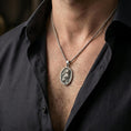 Load image into Gallery viewer, A 925 sterling silver cat pendant worn on the neck, oxidized look bringing depth to the cat relief and background texture.
