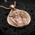 Load image into Gallery viewer, A rose gold plated Greek mythology coin pendant on volcanic rock, Perseus warrior scene with Medusa head detail.
