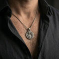 Load image into Gallery viewer, A 925 sterling silver Perseus and Medusa pendant worn on the neck, oxidized contrast highlighting the coin relief.
