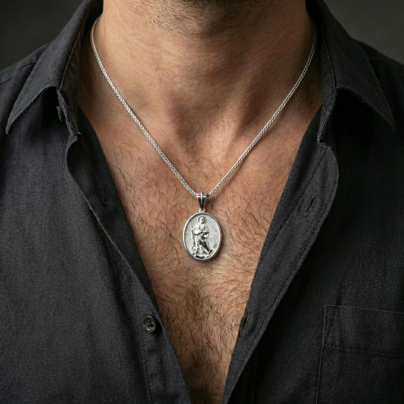 A polished 925 sterling silver Saint John the Evangelist necklace worn on the neck, oval saint medal on a chain for everyday wear.