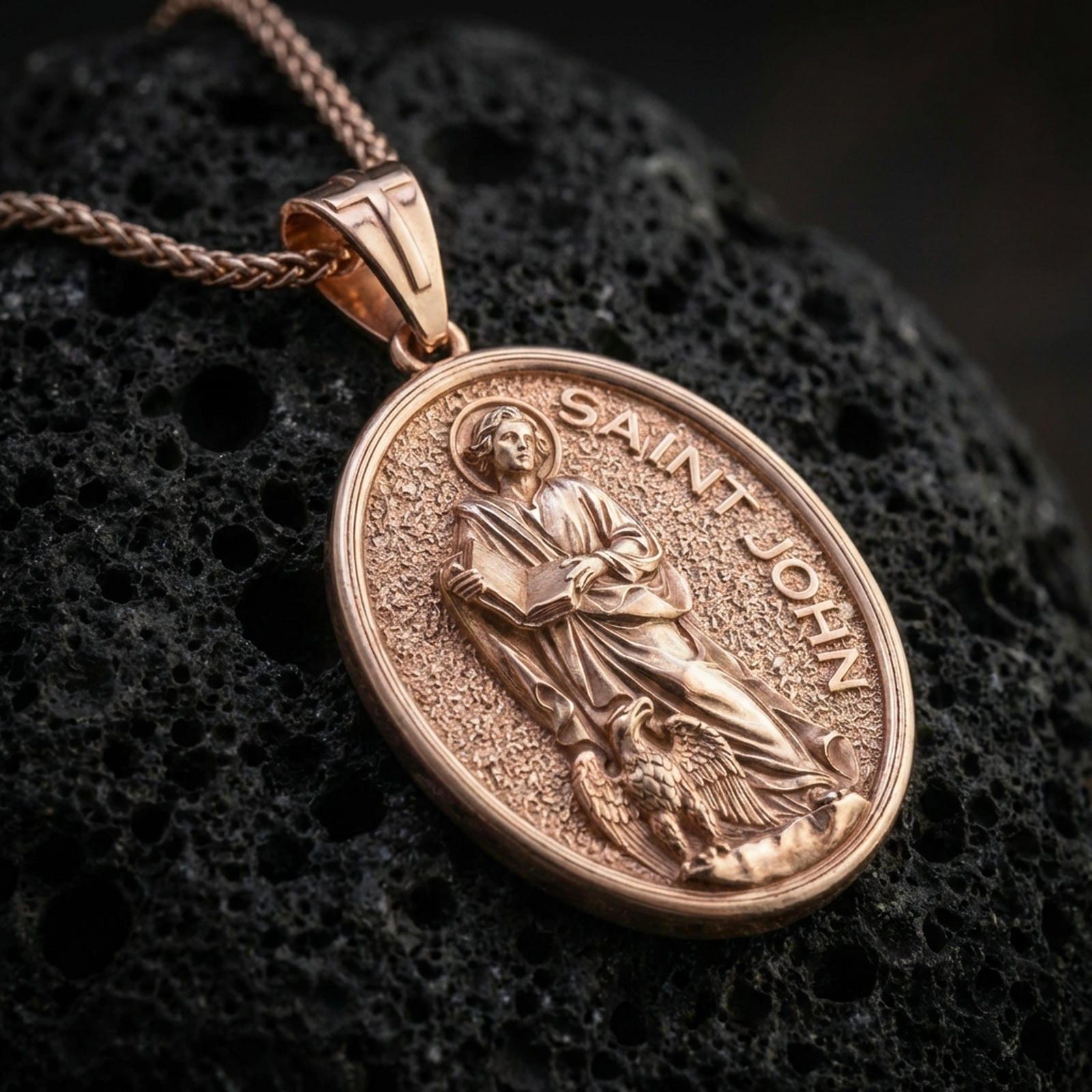 A rose gold plated Saint John the Evangelist pendant on volcanic rock, devotional oval medal with textured background.