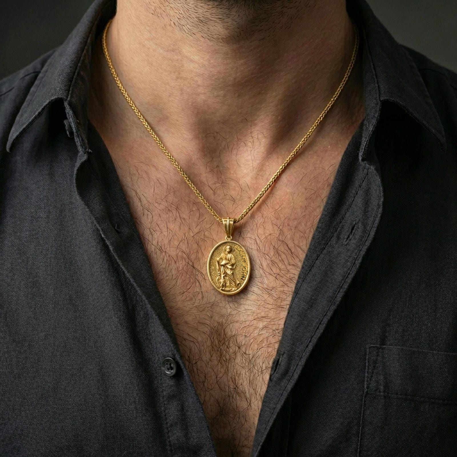 A gold plated Saint John the Evangelist pendant worn on the neck, Catholic devotional medal in an oval coin style.