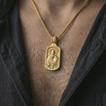 Load image into Gallery viewer, Gold plated Saint Paul dog tag pendant necklace worn on the neck, captured on a human model in a premium dark-toned lifestyle frame.
