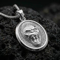 Load image into Gallery viewer, Polished silver gorilla necklace with detailed roaring primate face, sculpted fur texture, and oval statement medallion design placed on textured volcanic rock in a premium studio product shot
